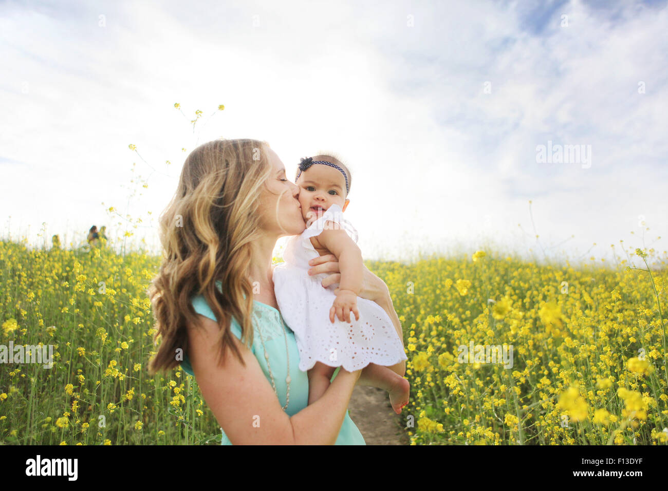Mutter küssen Babymädchen in Blumenwiese Stockfoto