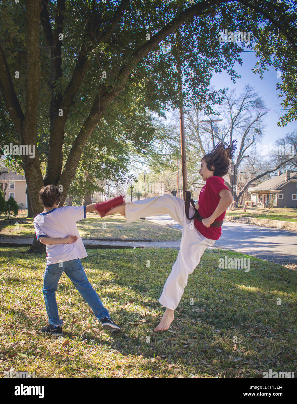Ein Junge ist einen Karate-tritt in die Luft, während außerhalb tun. Stockfoto
