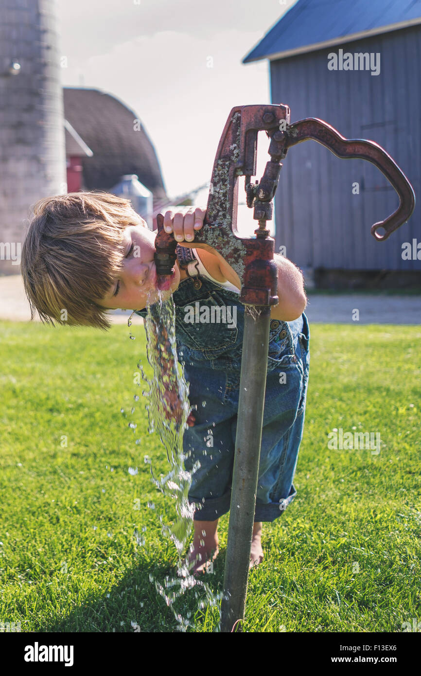 Junge Trinkwasser aus einem Outdoor-Leitung auf dem Bauernhof Stockfoto