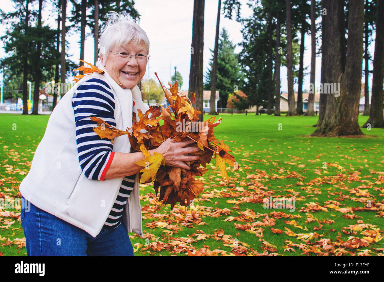 Ältere Frau mit Handvoll Herbst Blätter Stockfoto