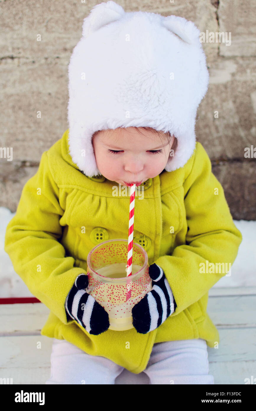 Mädchen im Winter draußen sitzen und einen Milchshake trinken Stockfoto