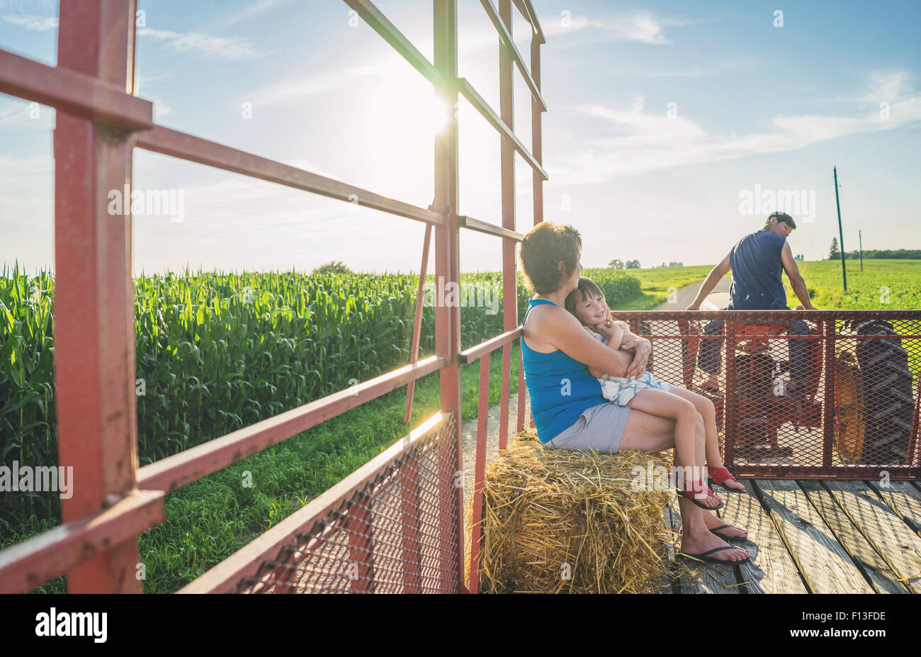 Mutter sitzt mit ihrer Tochter im Rücken eines Traktors, USA Stockfoto