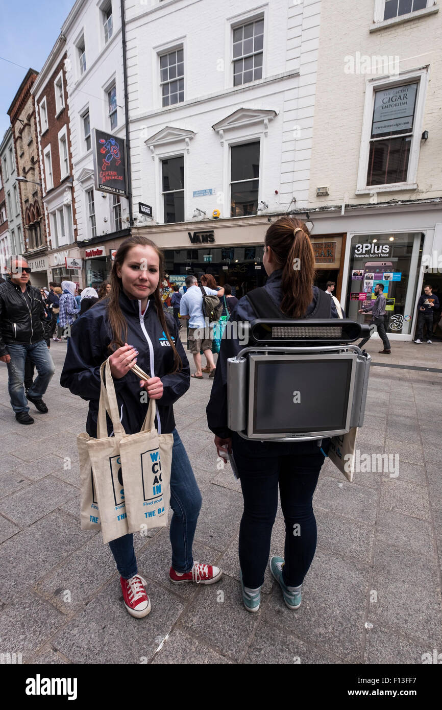 Zwei PR-Mädchen mit einem Raumzeitalter Monitor geschnallt zu ihr zurück und verteilen Geschenke an Passanten in der Grafton Street zur Förderung der Stockfoto