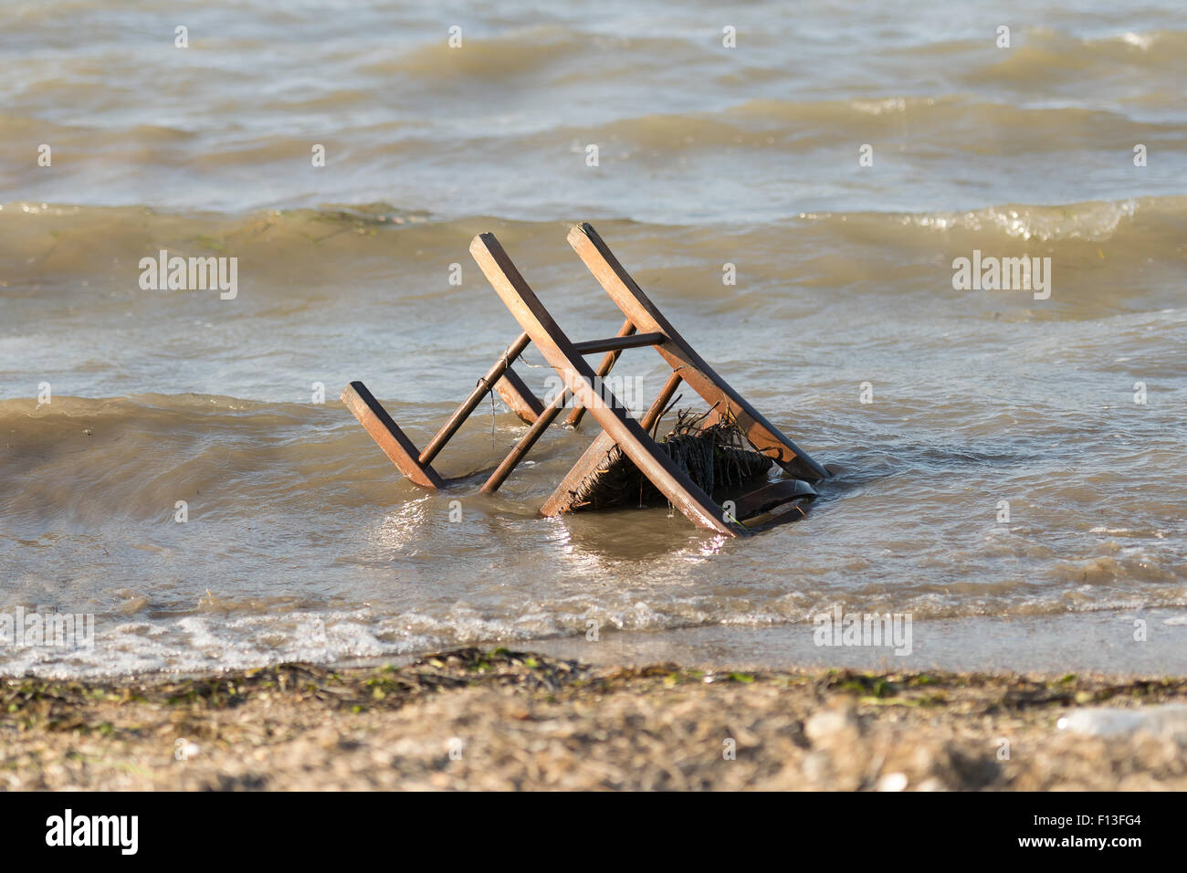 Verschmutzter Strand mit einem Stuhl drin. Stockfoto