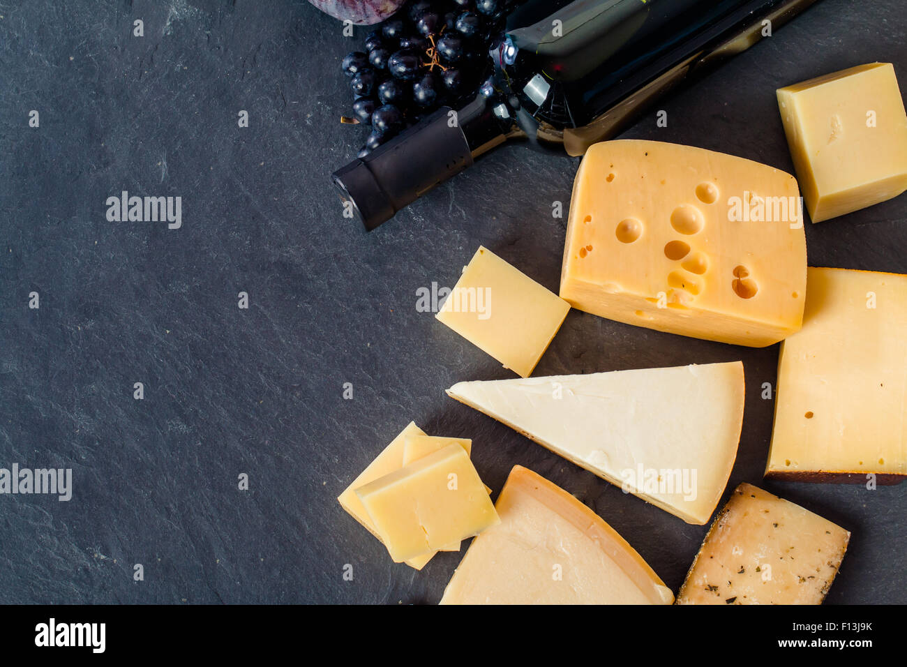Verschiedene Arten von Käse, roten Wein, Trauben und Figa am schwarzen Brett, Ansicht von oben Stockfoto