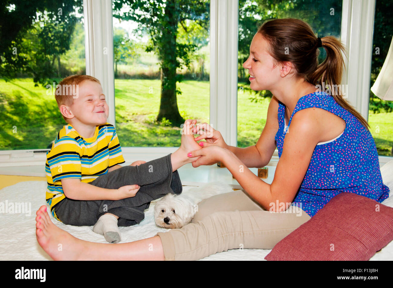 Junge versucht nicht zu lachen, während Fuß gekitzelt wird Stockfoto