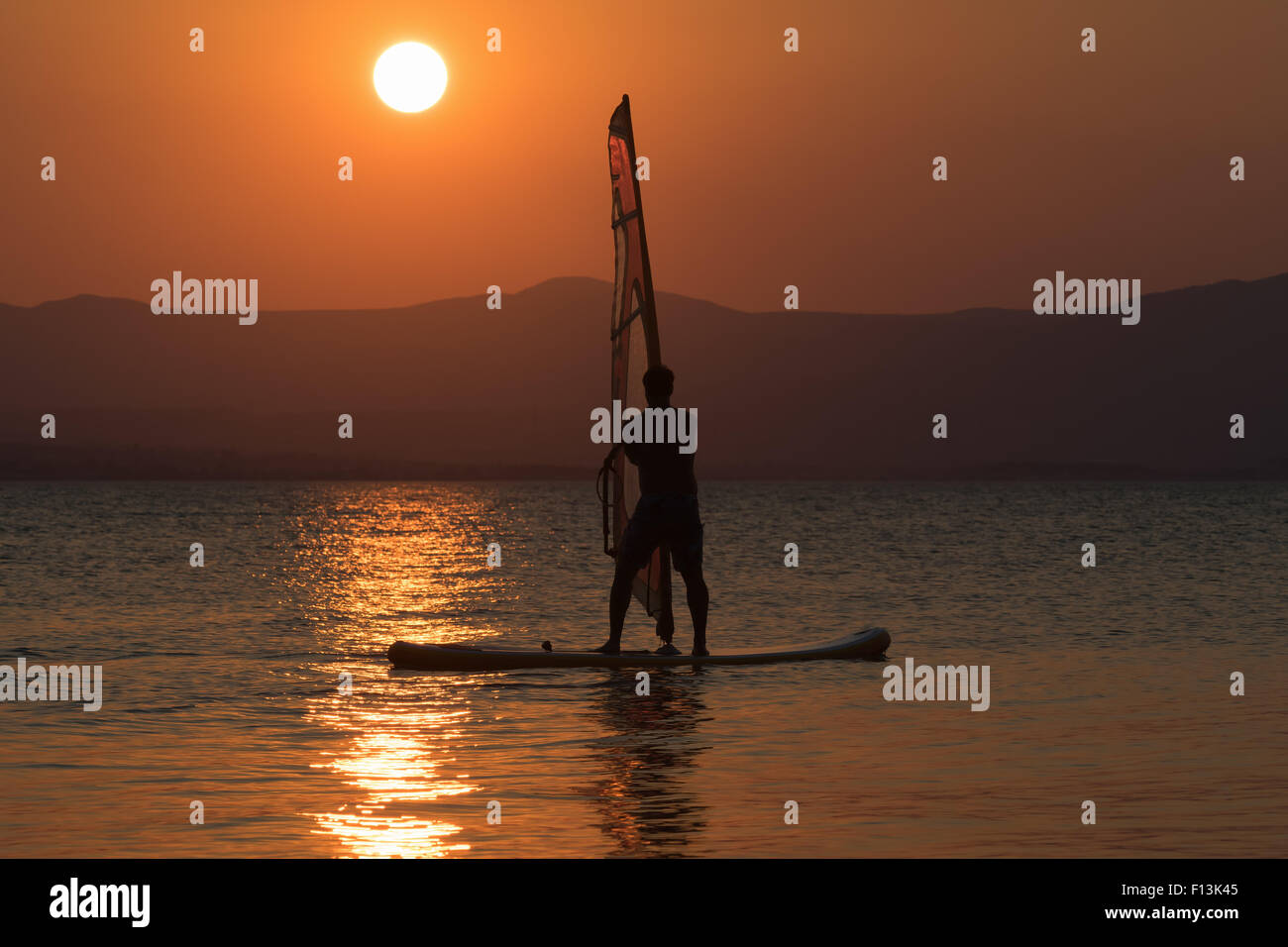 Surfen-Mann-Silhouette wieder einen wunderschönen Sonnenuntergang als Hintergrund. Stockfoto