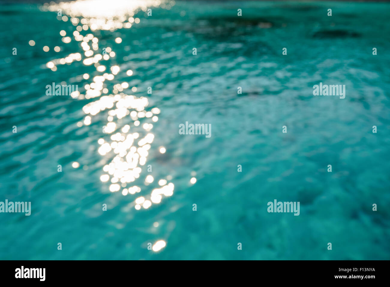 Verschwimmen Sie grün blau Meeresoberfläche mit reflektierenden Sonnenlicht Abend im Sommer für den Hintergrund Stockfoto