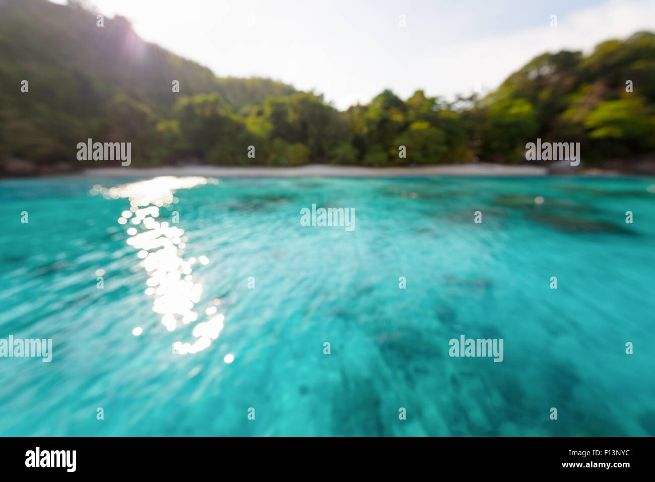 Verschwimmen Sie Strand und blauen Meeresoberfläche mit reflektierenden Sonnenlicht Abend im Sommer für den Hintergrund Stockfoto