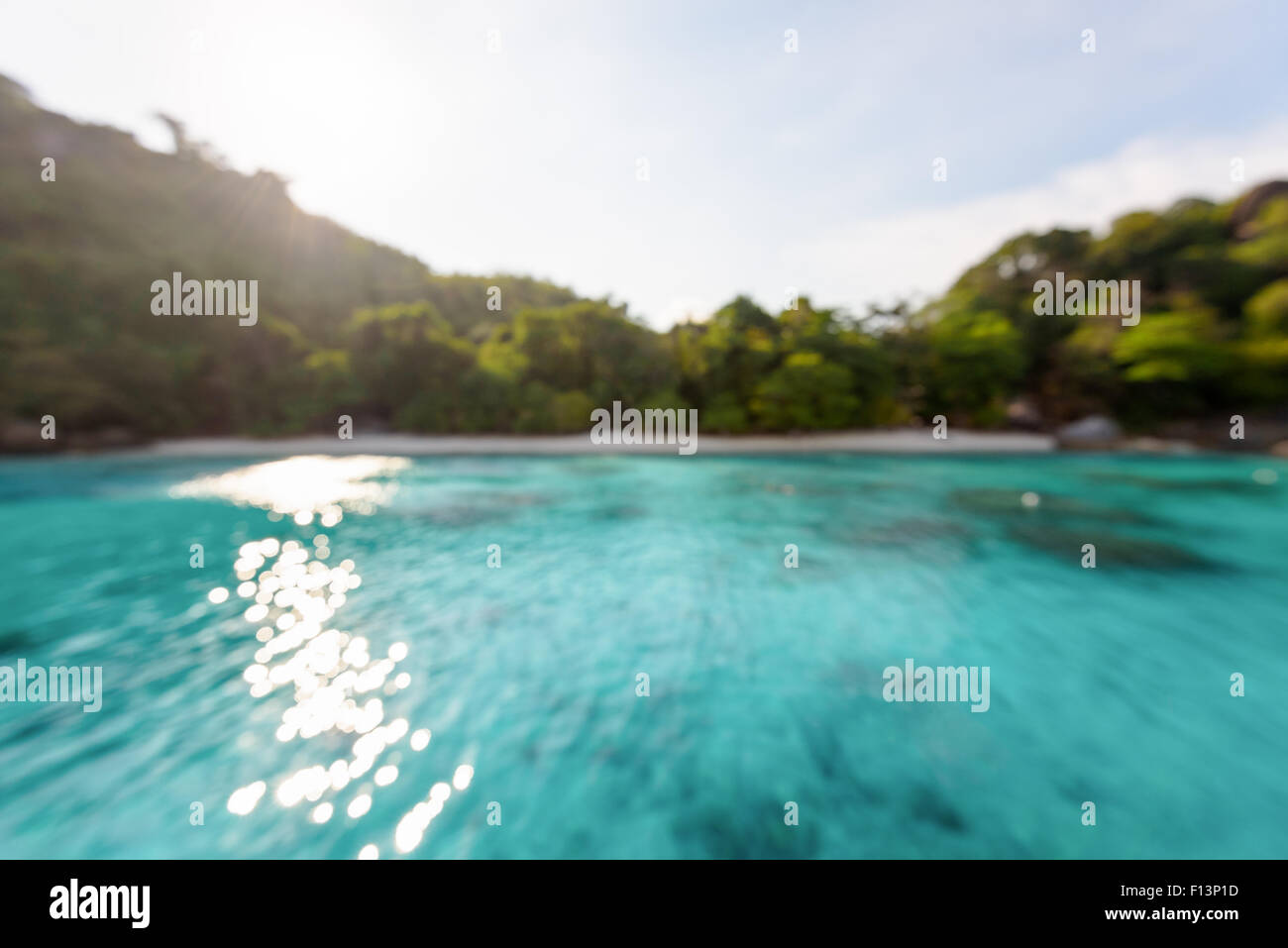 Verschwimmen Sie Strand und blauen Meeresoberfläche mit reflektierenden Sonnenlicht Abend im Sommer für den Hintergrund Stockfoto