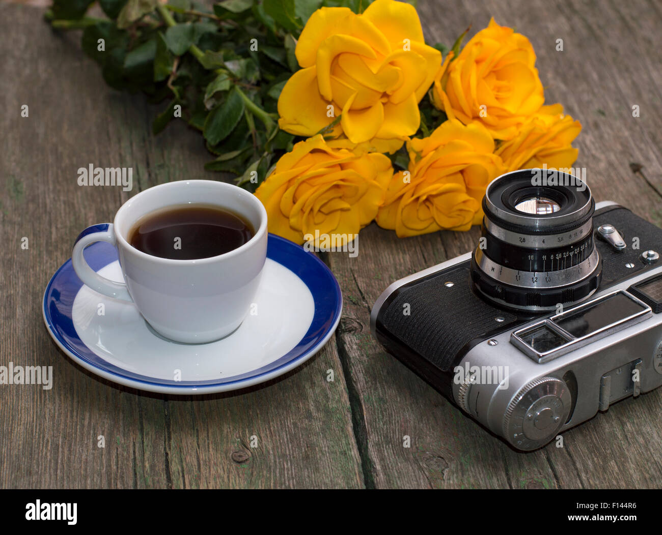 Bouquet von gelben Rosen, Tasse Kaffee und ein Retro-Kamera auf einem Tisch Stockfoto