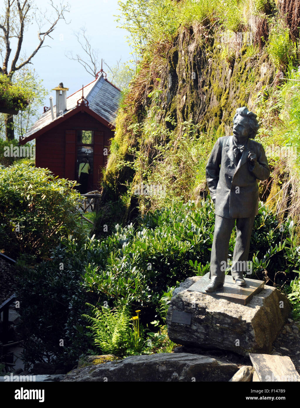 Bergen, Norwegen. Eine Statue des Komponisten Edvard Grieg mit seiner kompositorischen Hütte am See im Hintergrund. Stockfoto