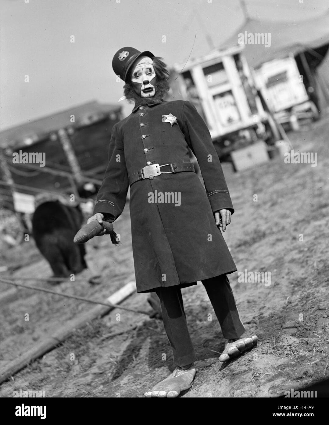 1920S 1930S VERKLEIDETE DARSTELLER ZIRKUSCLOWN ALS KEYSTONE COP BLICK IN DIE KAMERA Stockfoto