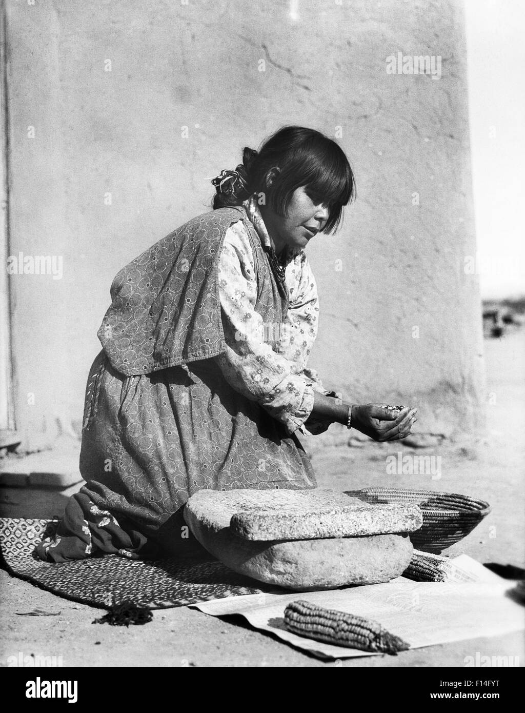 1930ER JAHREN INDIANISCHE FRAU SCHLEIFEN MAIS AUF STEIN METATE SAN ILDEFONSO PUEBLO NEW MEXICO USA Stockfoto