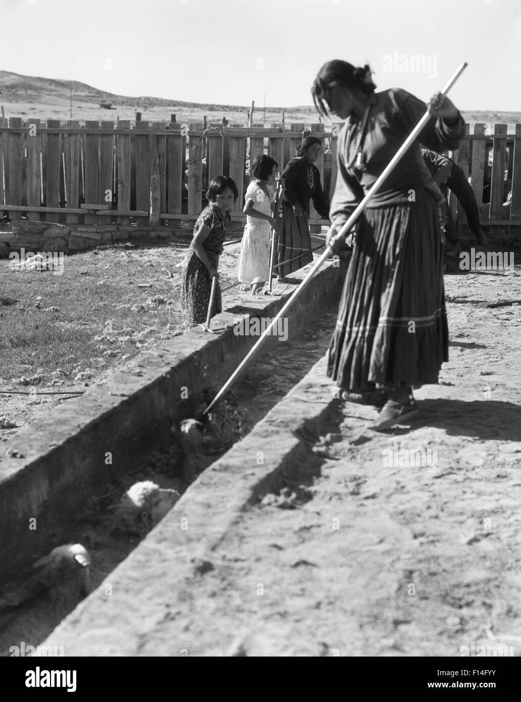 1930ER JAHREN INDIANISCHE FRAUEN KINDER FÜHRENDEN SCHAFE DURCH SCHAFE TAUCHEN IN TUBA CITY IN ARIZONA-NAVAJO-INDIANER-RESERVAT Stockfoto