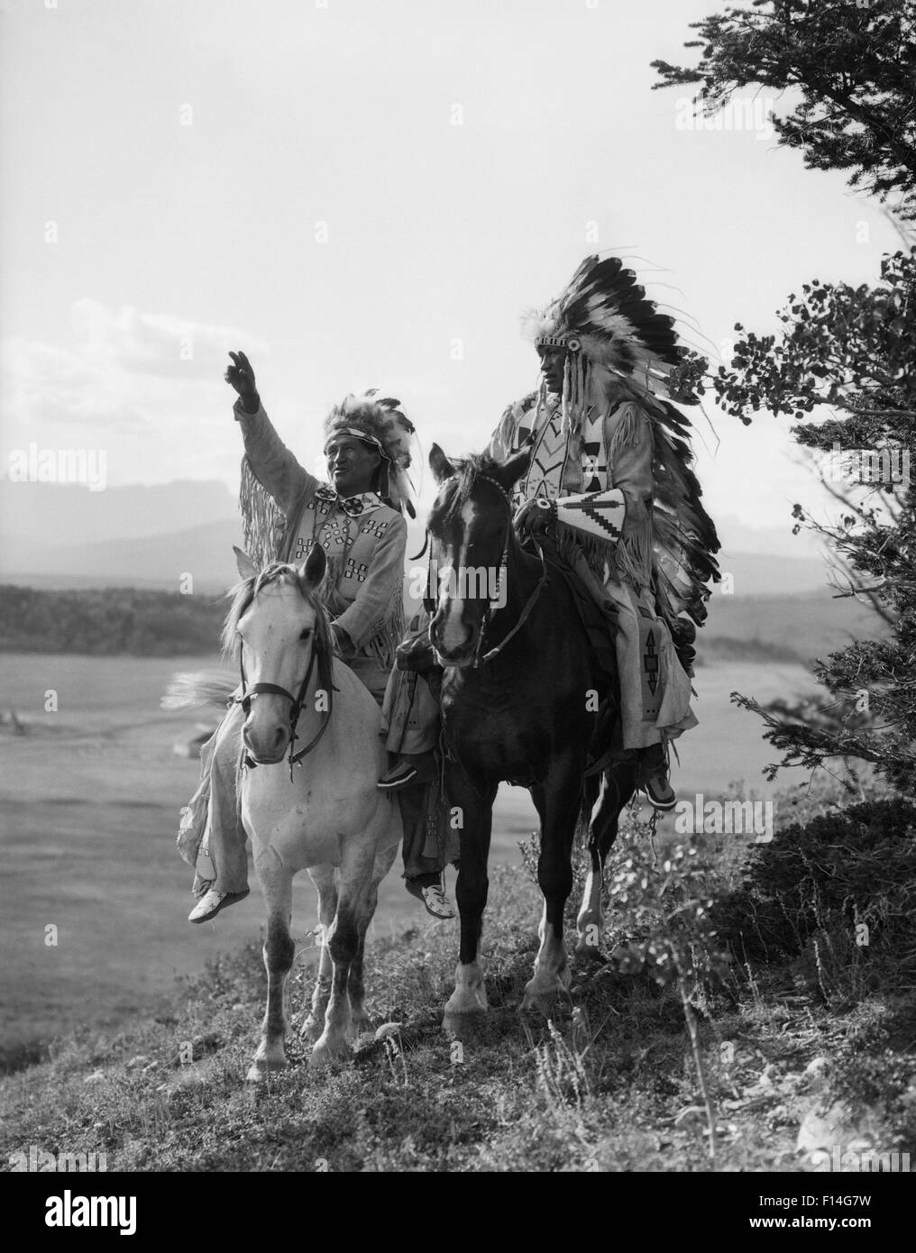 1920ER JAHREN ZWEI INDIANISCHEN INDISCHE MÄNNER AUF REITEN IN VOLLE FEDER KOPFSCHMUCK STONEY SIOUX STAMMES ALBERTA KANADA Stockfoto