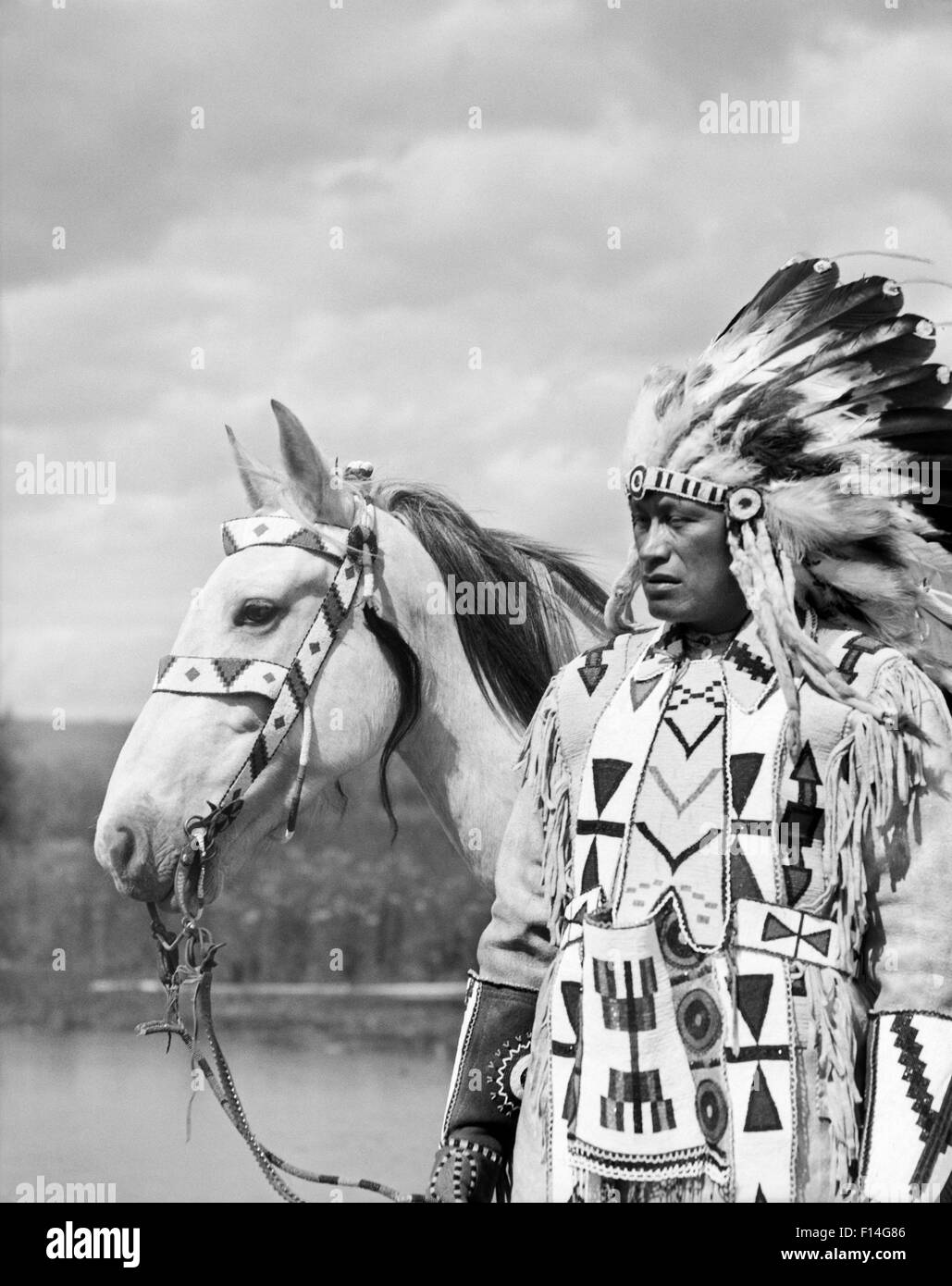 1920ER JAHRE PORTRAIT NATIVE AMERICAN INDIAN CHIEF VOLL FEDER KOPFSCHMUCK PERLEN KLEIDER PFERD STONEY SIOUX STAMMES ALBERTA KANADA Stockfoto