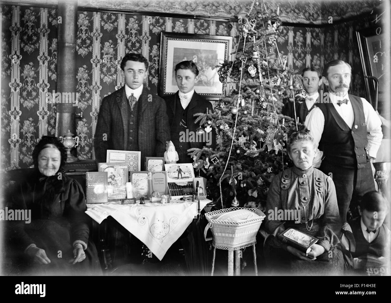 1890 1890S WENDE DES JAHRHUNDERTS GRUPPE PORTRAIT FAMILIE DREI GENERATIONEN POSING BY WEIHNACHTSBAUM GESCHENKE AUF TISCH Stockfoto