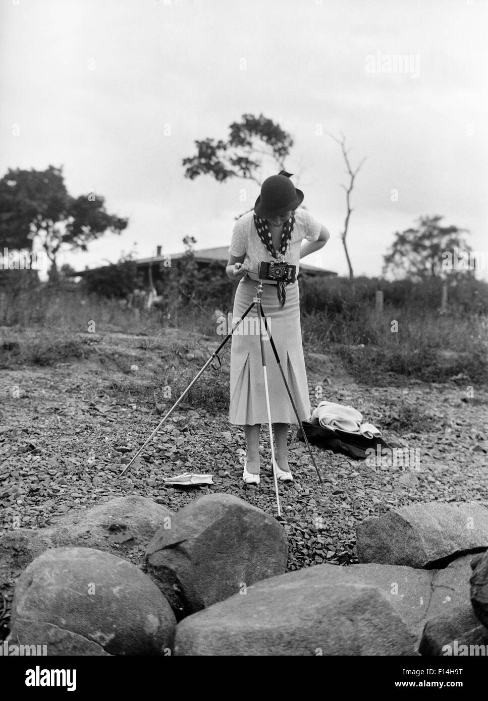 1930ER JAHRE ELEGANT GEKLEIDETE FRAU FOTOGRAF BLICK DURCH DEN SUCHER DER KAMERA AUF STATIV Stockfoto