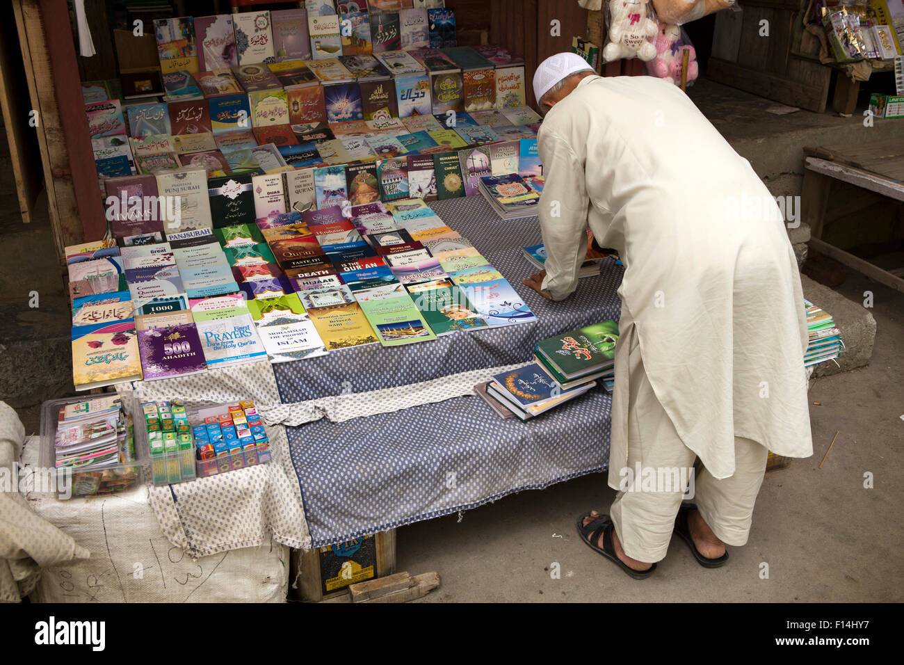 Indien, Jammu & Kaschmir, Srinagar, Hazratbal Basar, religiöse Buchhandlung Inhaber Bücher auf dem Display Reinigung Stockfoto