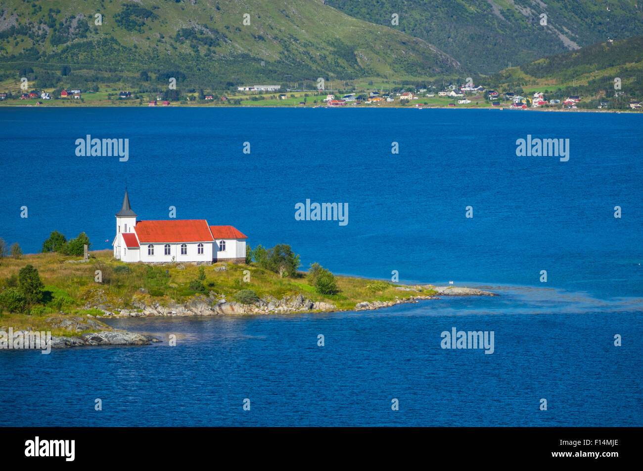 Weiße Kirche mit rotem Dach in den Bergen und Fjord Einstellung, Lofoten, Norwegen Stockfoto