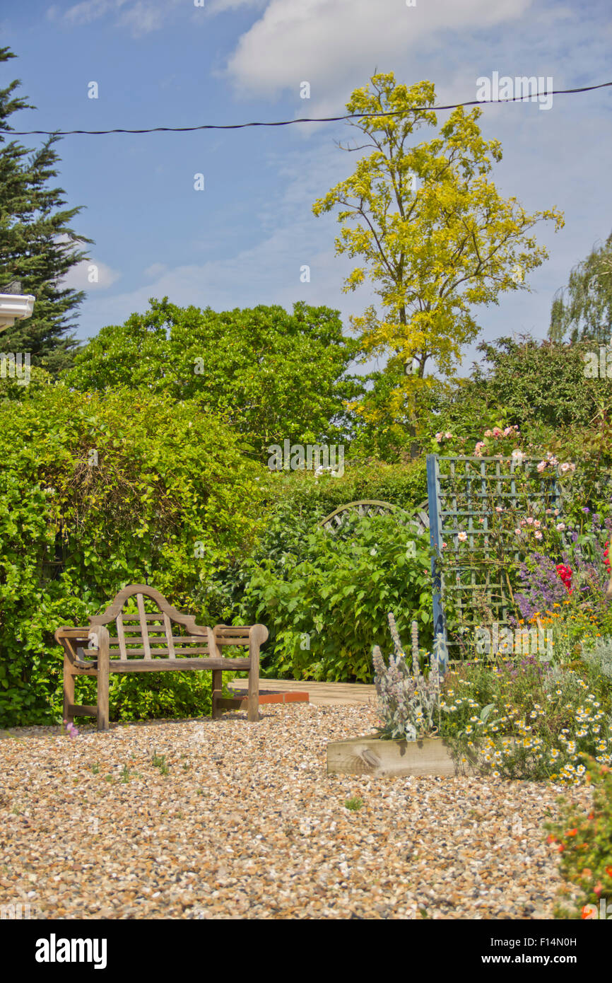 Handgemachte braune Holzbank in einem englischen Landhaus-Garten Stockfoto