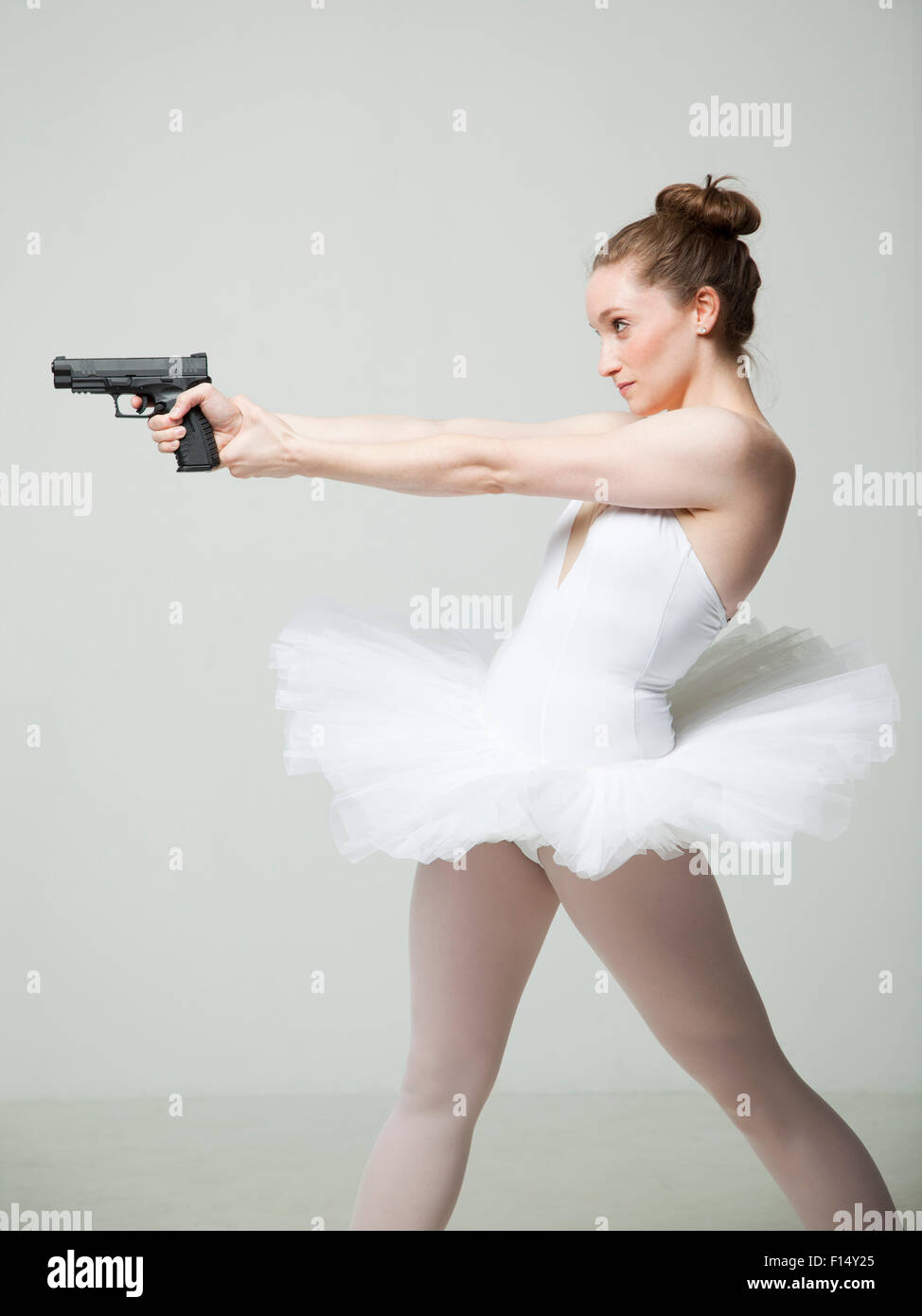 Studioaufnahme von Ballett-Tänzerin mit Pistole Stockfoto