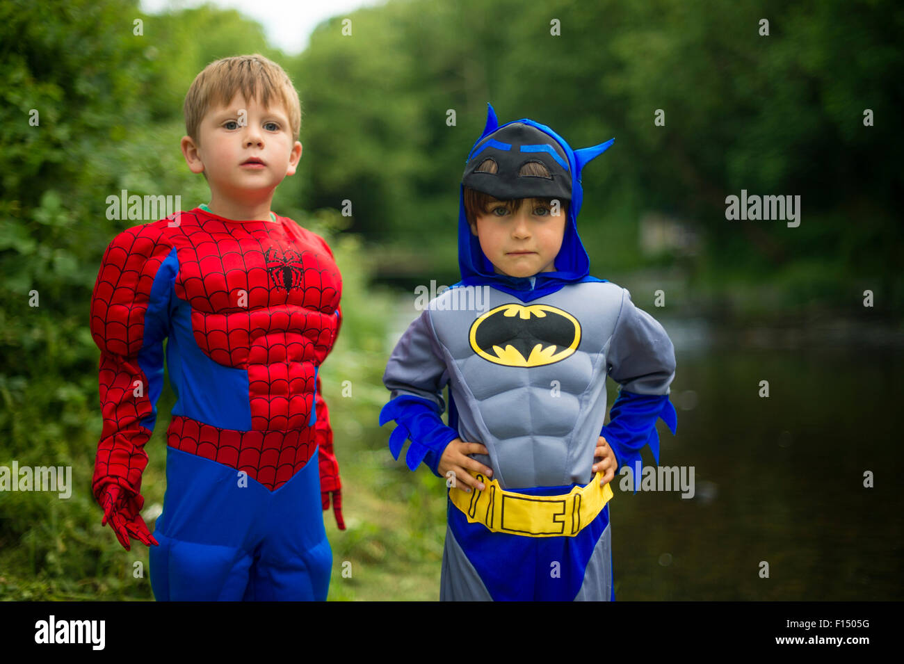 Batman und Spiderman Kinderspiele: zwei pre-Teen jungen Kindern im Grundschulalter spielen im Freien an einem Sommerabend, verkleidet als Comic-Buch-Superhelden Batman und Spiderman. UK Stockfoto