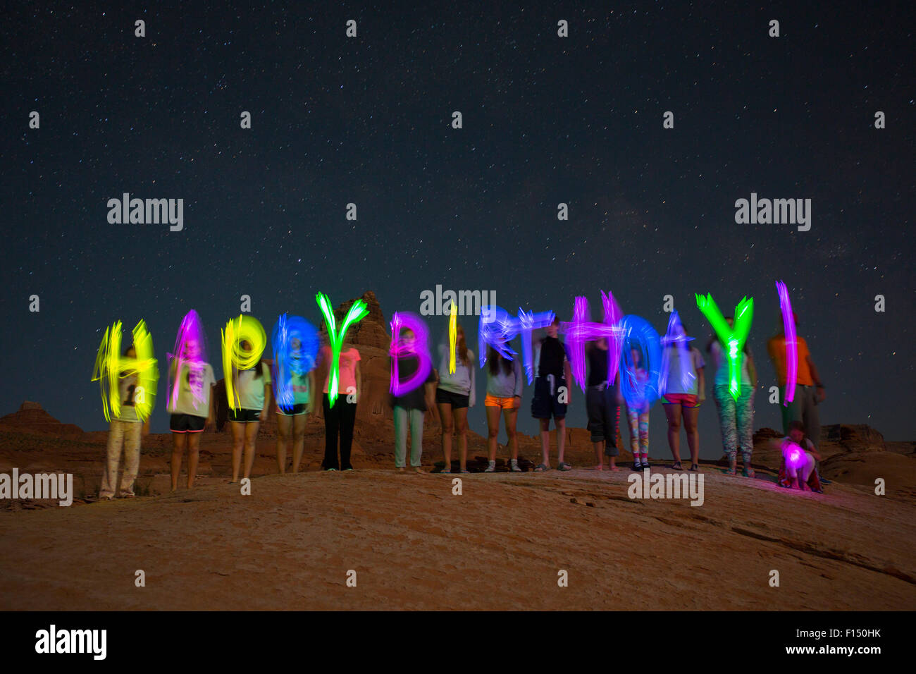 Zeitraffer Zeitansicht Freunde schreiben alles Gute zum Geburtstag auf abgelegenen Wüste Hügel unter Sternenhimmel Stockfoto