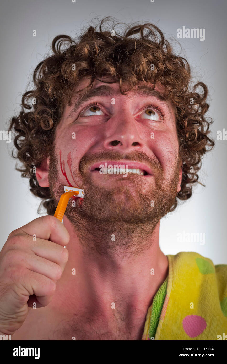 Dummer bärtiger Mann schneidet sein Gesicht beim Rasieren seinen Bart Stockfoto