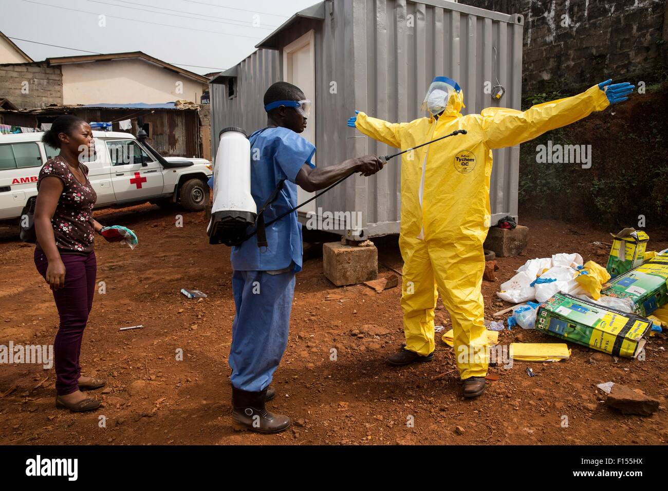 Ein Fahrer des Krankenwagens in Schutzkleidung wird mit Chlor desinfiziert, nach der Rückkehr aus dem Transport von Ebola Opfer zu einem Behandlungszentrum 15. Dezember 2014 in Freetown, Sierra Leone. Stockfoto