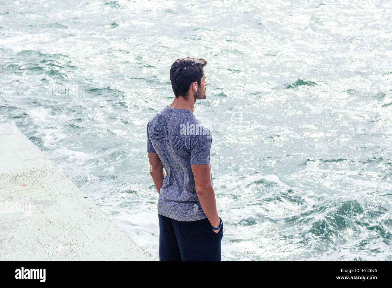 Porträt eines jungen Mannes in Sportbekleidung steht in der Nähe von Meer Stockfoto