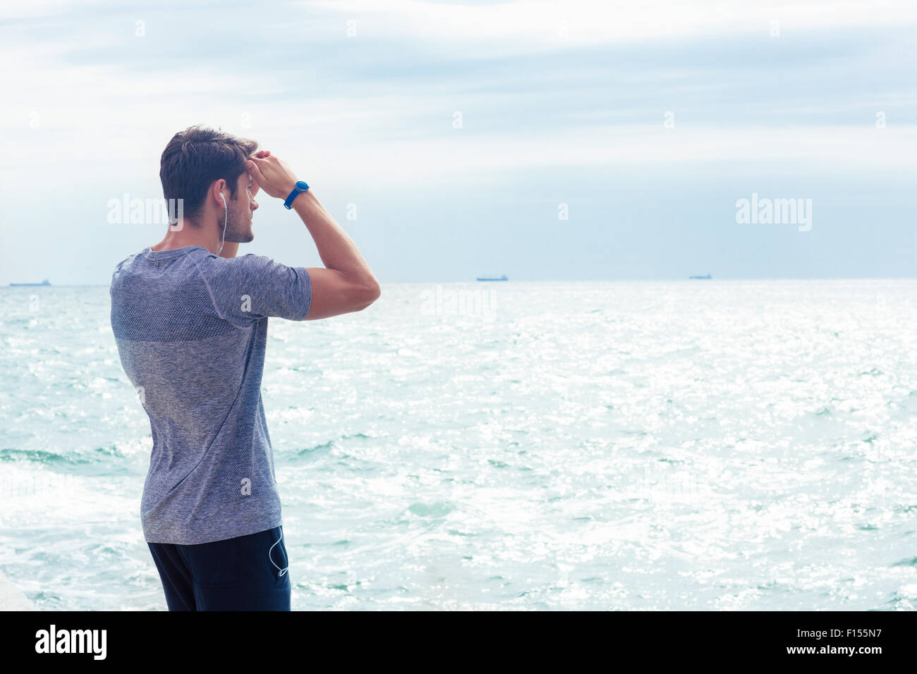 Porträt eines Mannes in Sportbekleidung mit Blick auf das Meer im freien Stockfoto