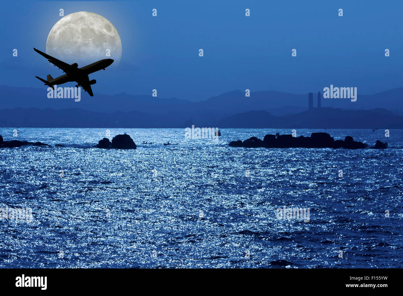 Flugzeug fliegen über dem Ozean im Mondlicht Stockfoto