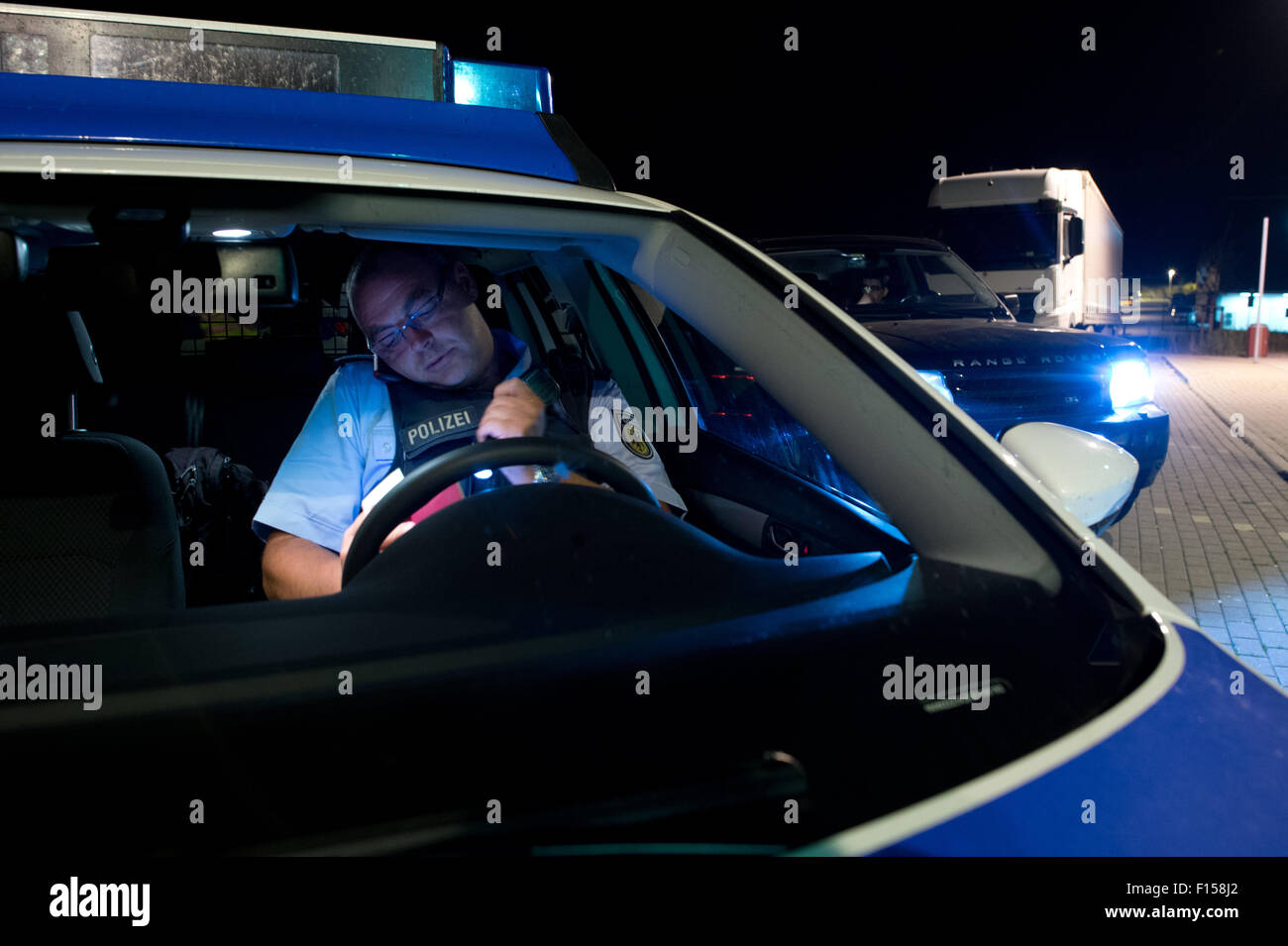 Polizist Torsten Bastian überprüft die Identität einer Person in seiner Nachtschicht auf dem Rastplatz "Am Heidenholz" in der Nähe der Bundesrepublik Polizeistation Breitenau in Bad Gottleuba-Berggießhuebel, Deutschland, 24. August 2015. Foto: ARNO BURGI/dpa Stockfoto