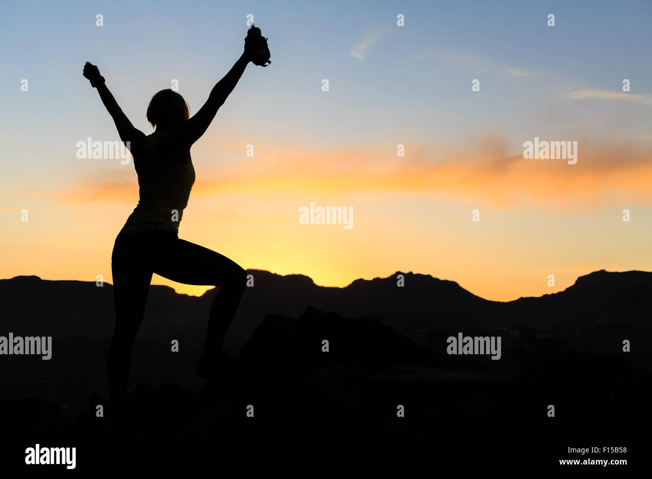 Frau Wandern Silhouette im Sonnenuntergang, Berge und Meer. Weibliche Wanderer, Bergsteiger oder Trailläufer mit ausgestreckten auf Berg Stockfoto