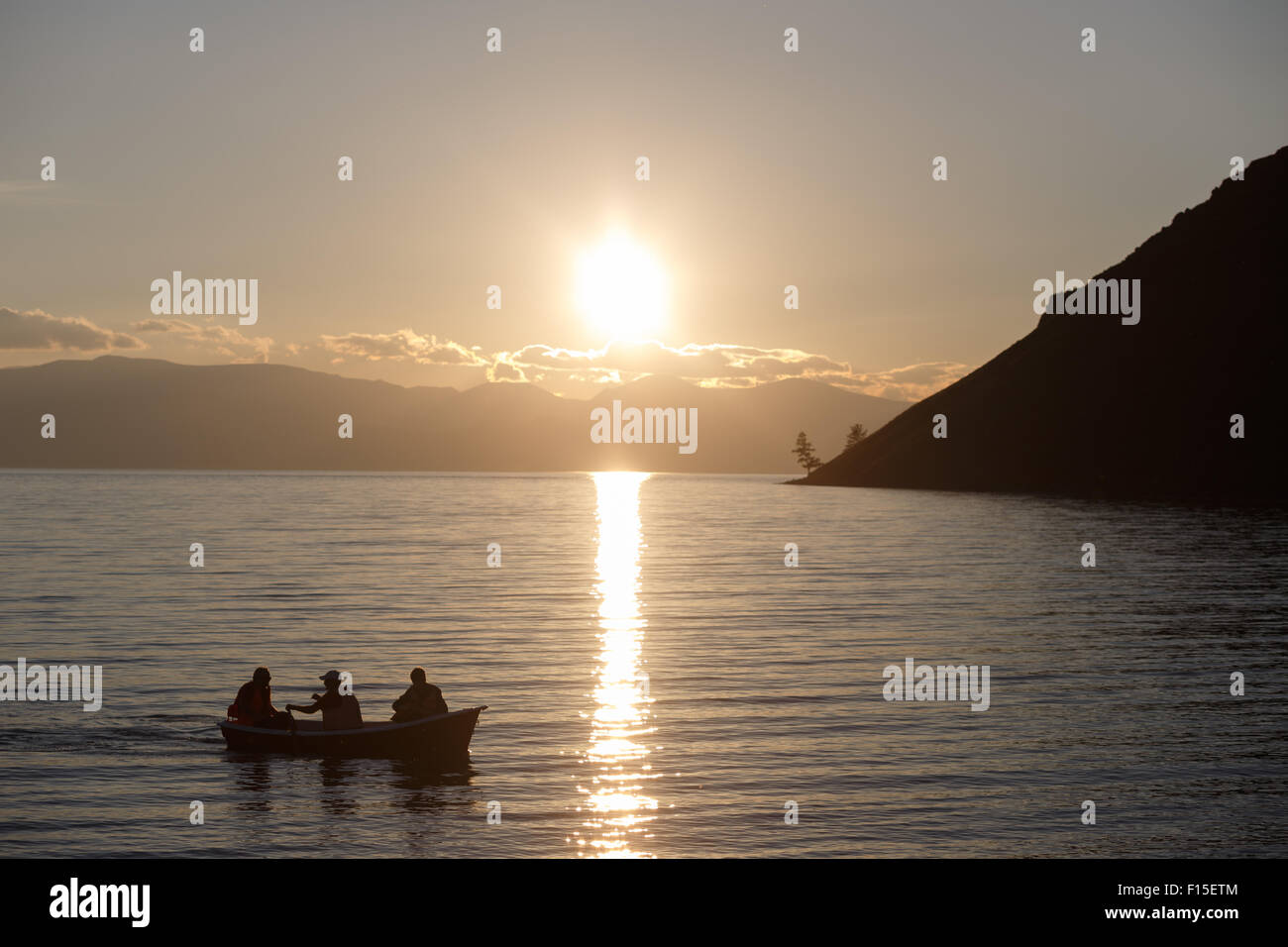 Menschen, die bei Sonnenuntergang in einem Boot auf einem Bergsee Fischen. Stockfoto
