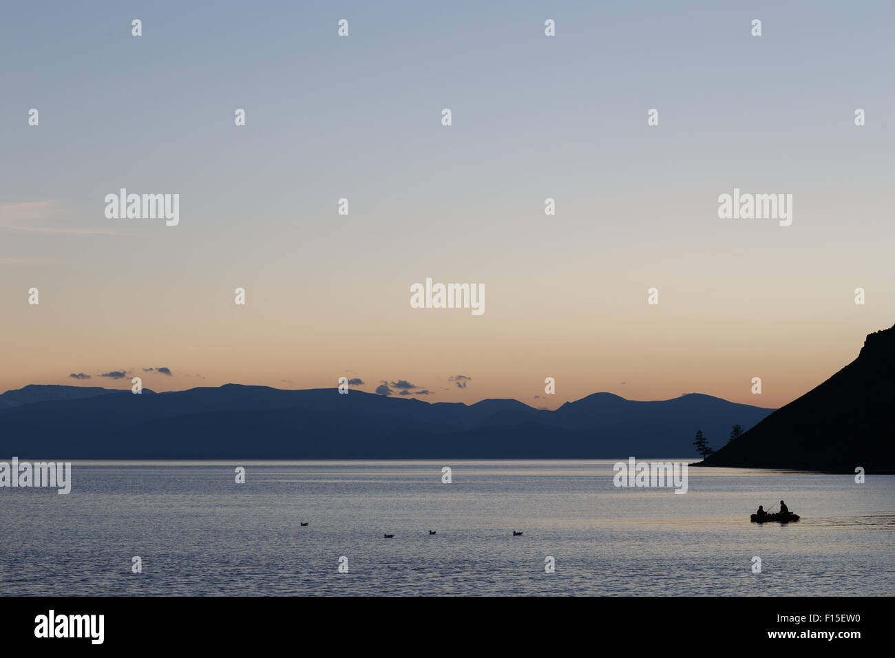 Menschen, die bei Sonnenuntergang in einem Boot auf einem Bergsee Fischen. Stockfoto