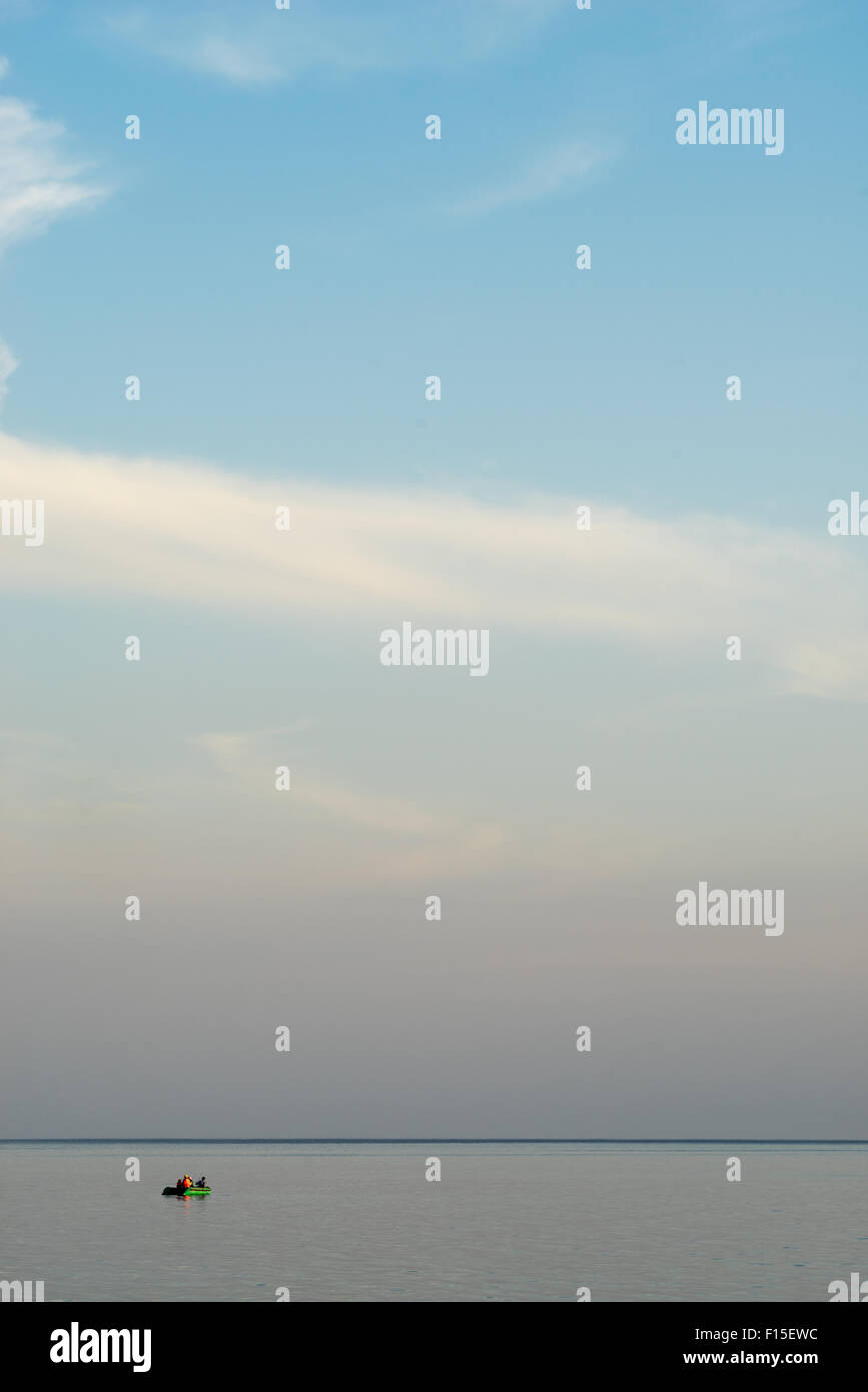 Menschen, die bei Sonnenuntergang in einem Boot auf einem Bergsee Fischen. Stockfoto