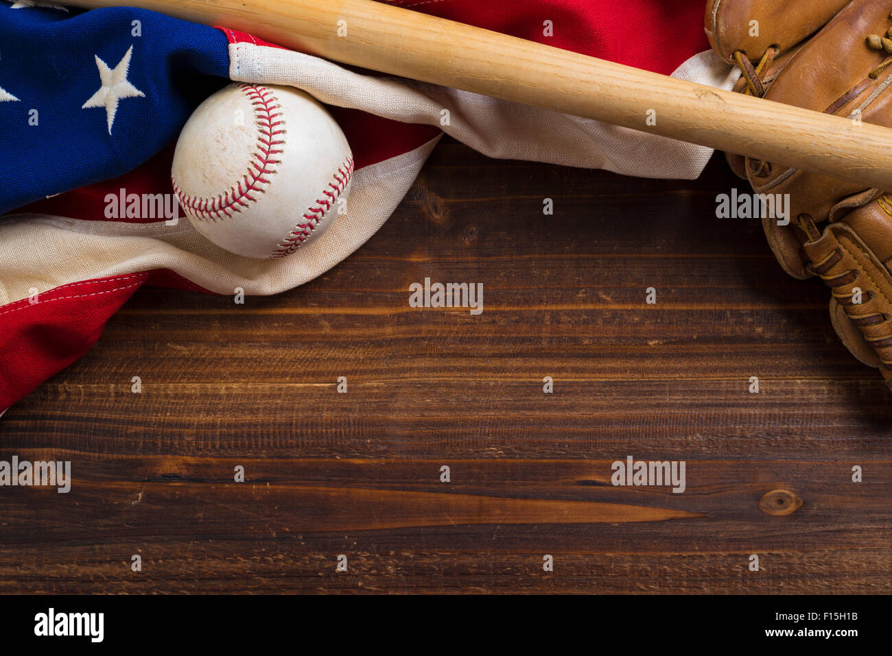 Eine alte, antike amerikanische Flagge mit Vintage Baseball-Ausrüstung auf einer Holzbank Stockfoto