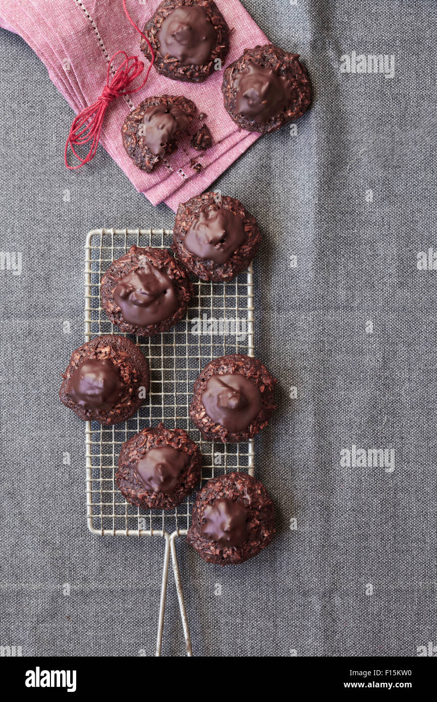 Schokolade, Kokos Makronen Cookies auf ein Kuchengitter mit rosa, Stoffserviette und Bindfäden, Studio gedreht auf einem grauen Hintergrund Stockfoto