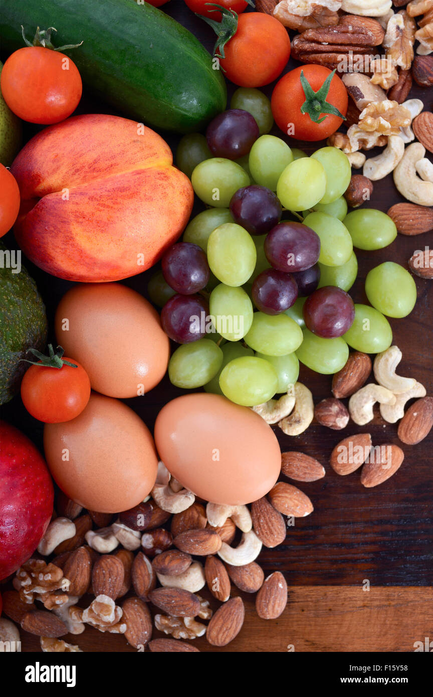 Gesunde Ernährung mit frischem Obst, Äpfel, Birnen, Avocados, Weintrauben, Eiern, Nüssen, Tomaten Gurken auf einem rustikalen Holz Hintergrund. Stockfoto