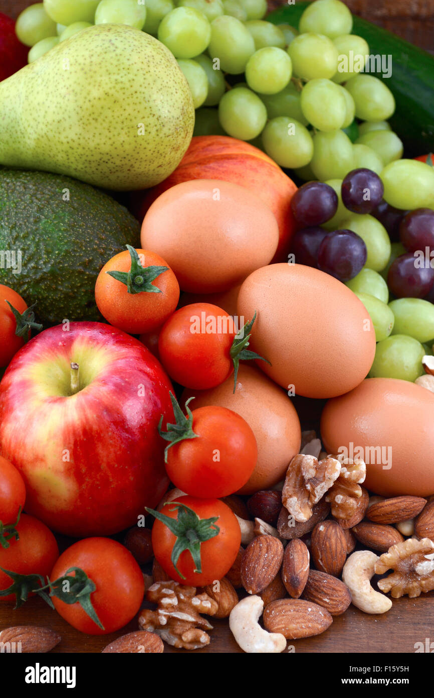 Gesunde Ernährung mit frischem Obst, Äpfel, Birnen, Avocados, Weintrauben, Eiern, Nüssen, Tomaten Gurken auf einem rustikalen Holz Hintergrund. Stockfoto