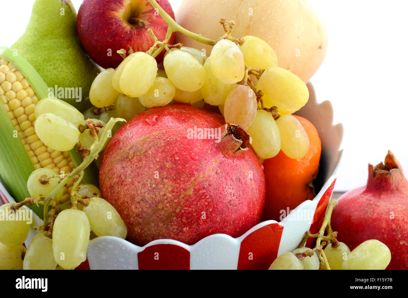 Schüssel mit Thanksgiving fallen Obst und Gemüse mit Granatapfel, Kaki, Äpfel, Trauben und Mais in roten und weißen Keramik Stockfoto