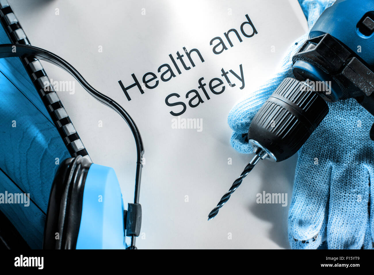 Bohrer, Ohrhörer und Handschuhe auf hölzernen Hintergrund Stockfoto