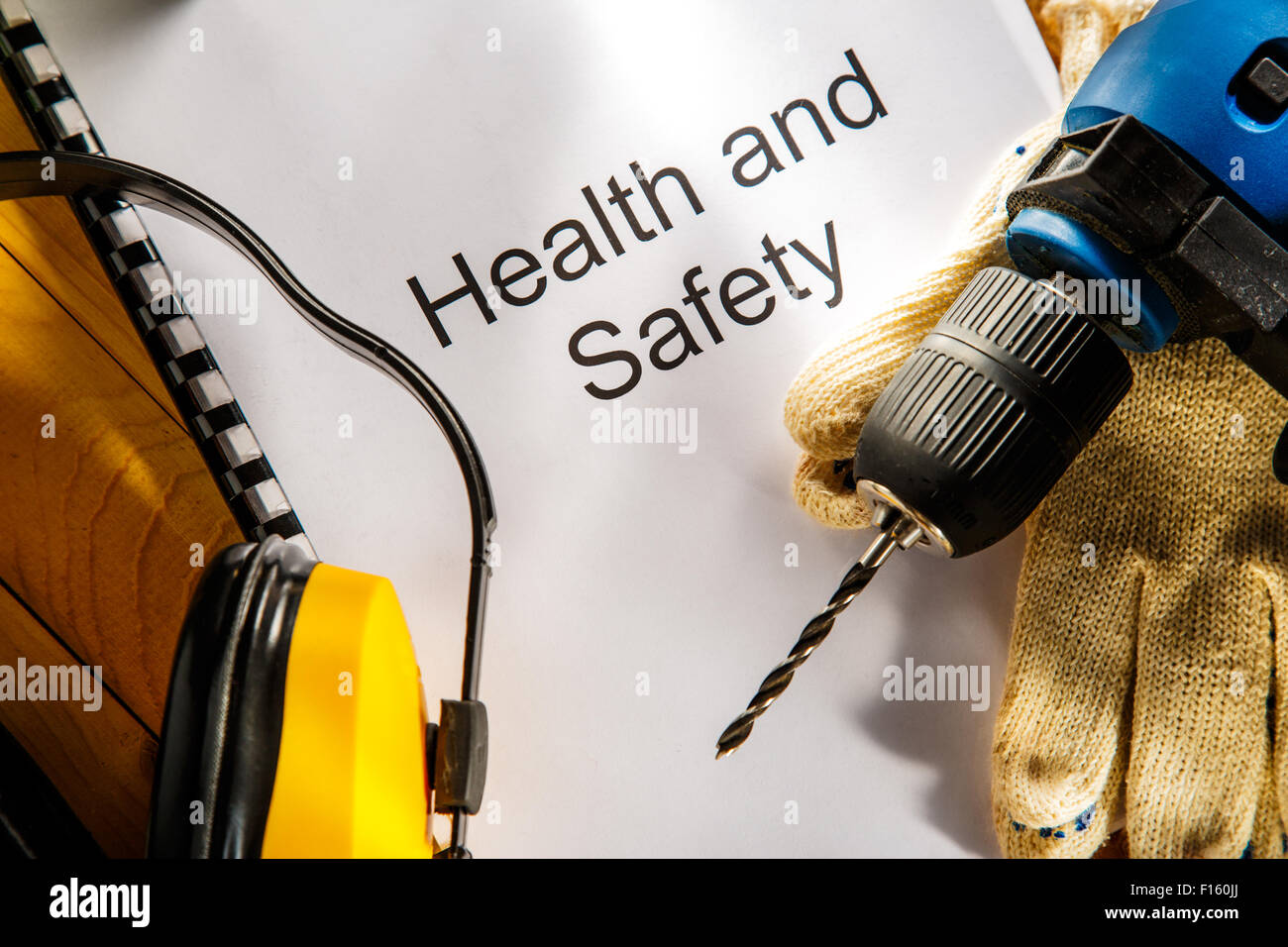 Bohrer, Ohrhörer und Handschuhe auf hölzernen Hintergrund Stockfoto