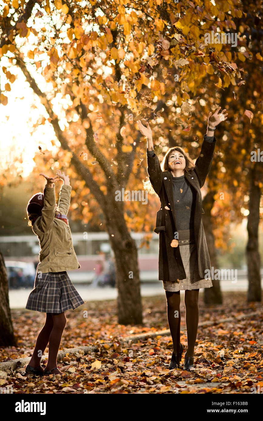 Vertikale Foto gerne schönes kleine Mädchen mit Mather werfen herbstliche Laub im park Stockfoto
