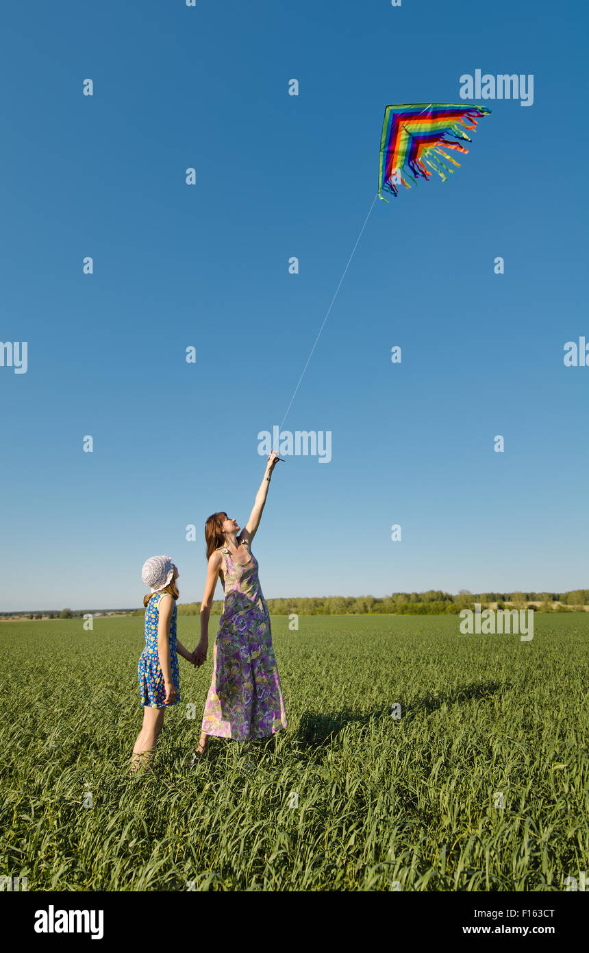 Fröhliches junges Mädchen mit Mutter Kiteflying, auf die Natur in Sommertag Stockfoto