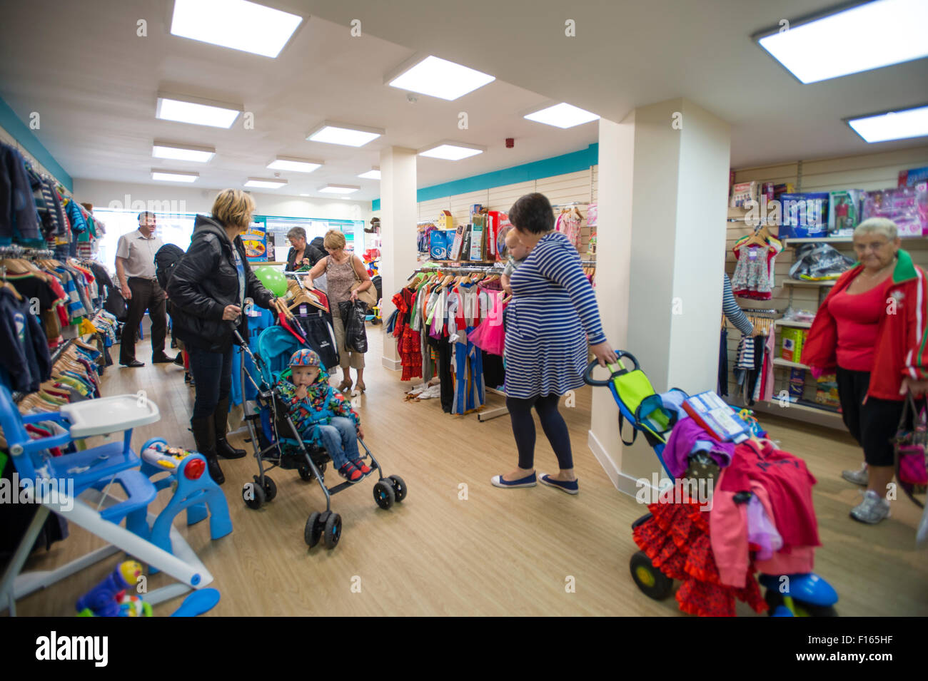 Frauen Shopper suchen Schnäppchen billig Kinder Kleidung in einen neuen Zweig der Barnardo Nächstenliebe Kindermoden Geschäft in Aberystwyth Wales UK Stockfoto