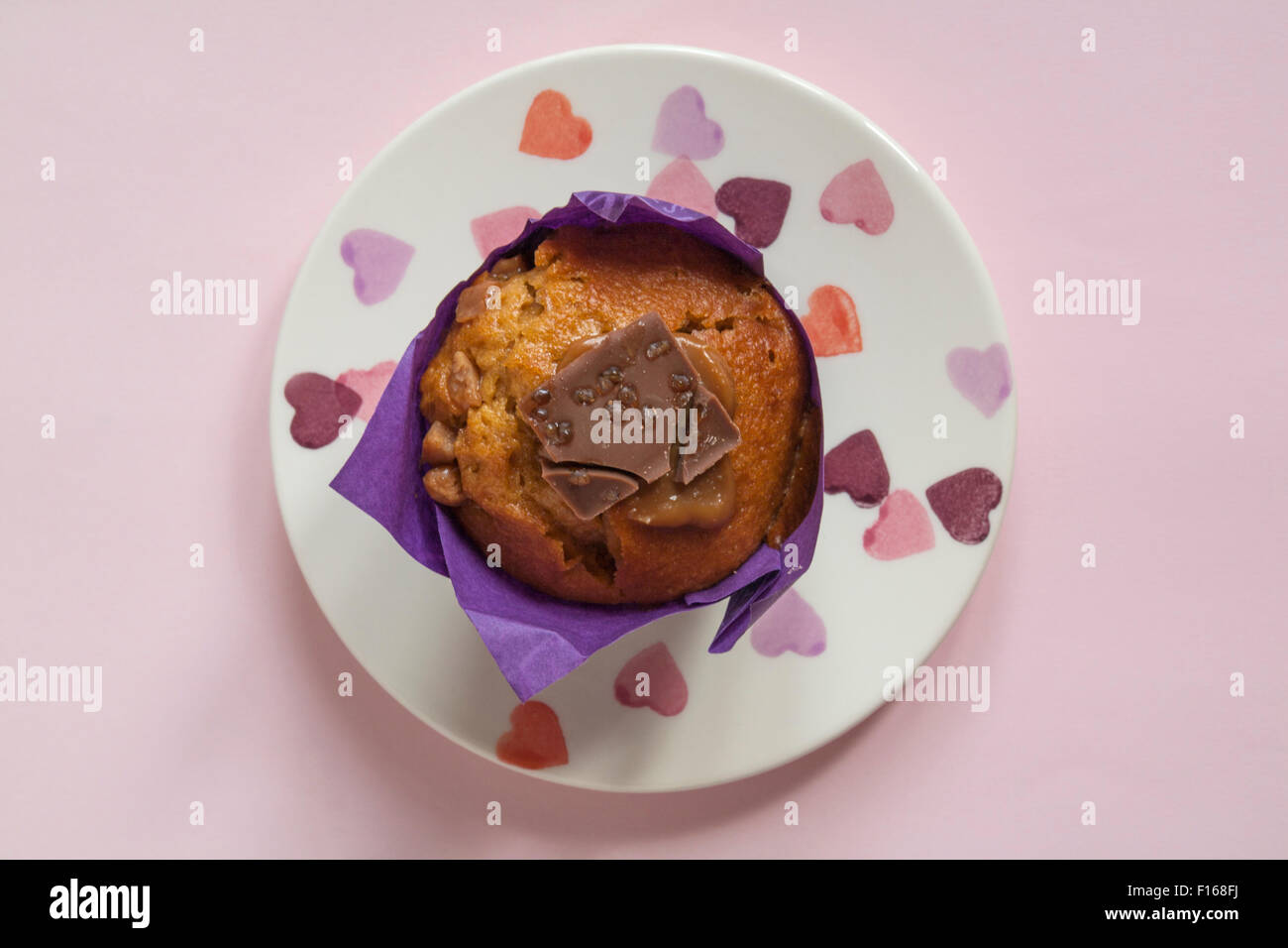 Sainsburys den Unterschied schmecken gesalzen Karamell muffin auf Herz Platte isoliert auf rosa Hintergrund Stockfoto